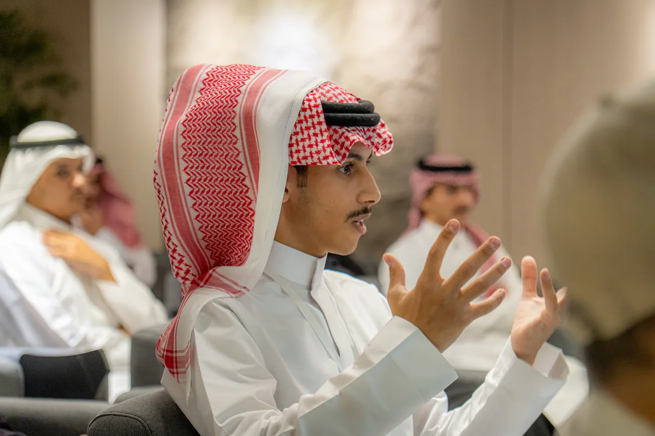 عضو شاب يطرح سؤالًا ويداه مفتوحتان، والحضور خلفه