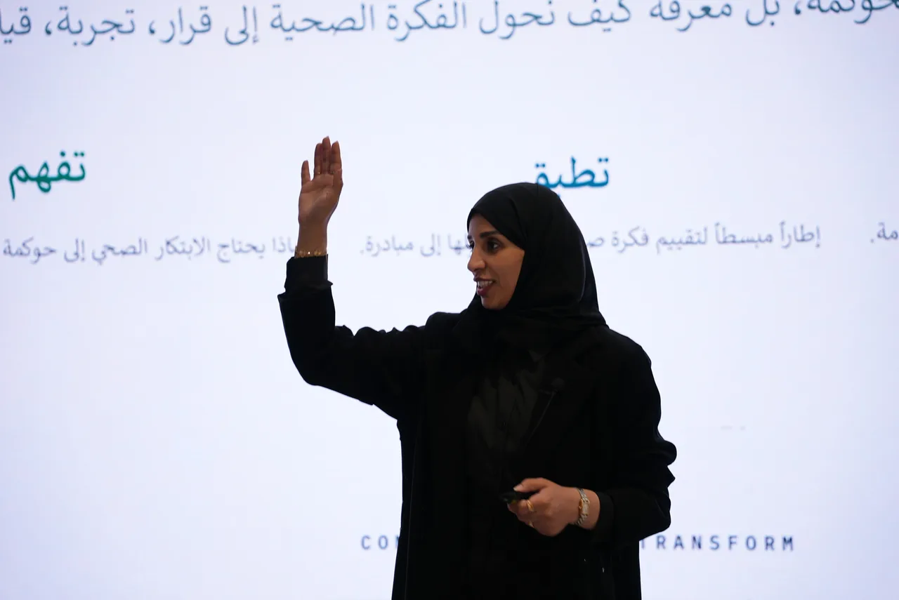 المتحدثة ترفع يدها وهي تشرح أمام الشاشة